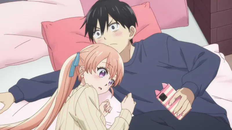 Erika Amano holds a pink smartphone while lying comfortably on a bed next to a wide-eyed, surprised Nagi Umino.