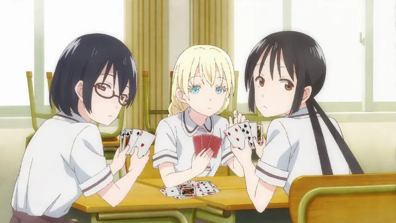 Hanako, Olivia, and Kasumi sit at a school desk playing a card game with serious expressions in the deceptive comedy Asobi Asobase.