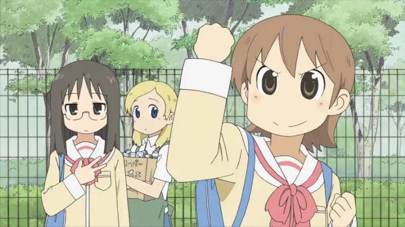 Yuuko raises her fist enthusiastically while Mai and Mio watch her quietly near a green park fence in the surreal comedy Nichijou.