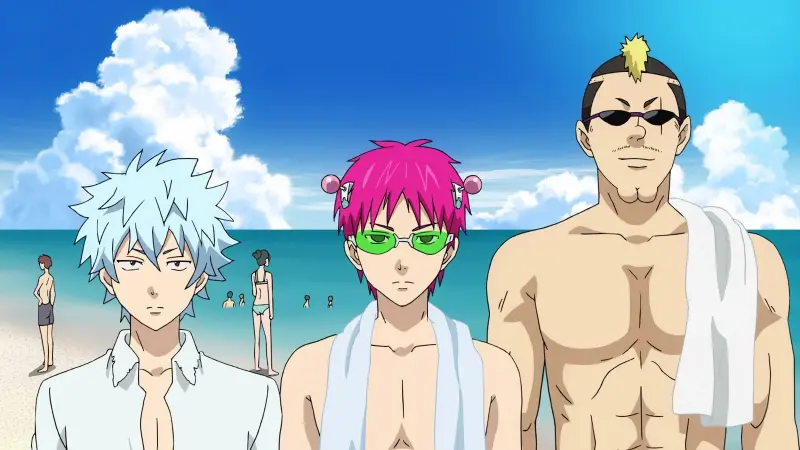 Kusuo Saiki stands on a sandy beach wearing green glasses alongside his classmates Kaido and Nendo in The Disastrous Life of Saiki K.