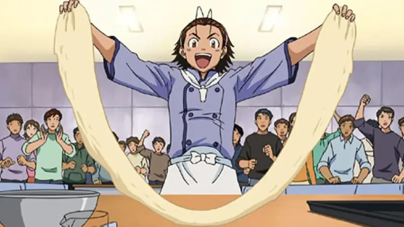 Azuma Kazuma proudly stretching bread dough high in the air in front of a cheering audience.