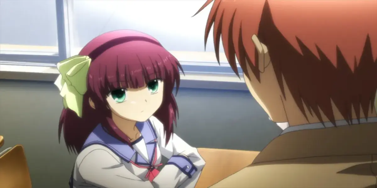 Yuri Nakamura sits at a classroom desk looking intently at Yuzuru Otonashi in the anime Angel Beats!.
