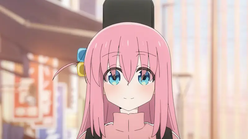 Bocchi the Rock! protagonist Hitori Gotoh wearing her signature pink tracksuit while standing on a city street.
