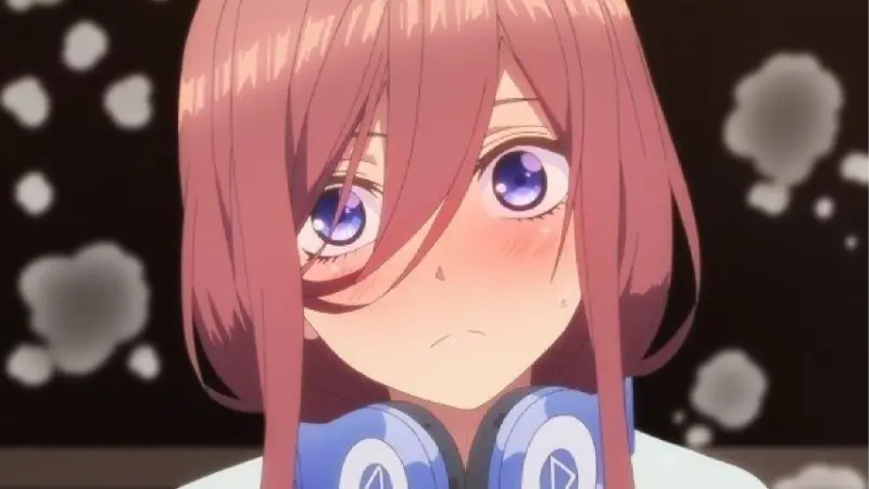 The Quintessential Quintuplets features Miku Nakano blushing heavily while wearing her blue headphones.