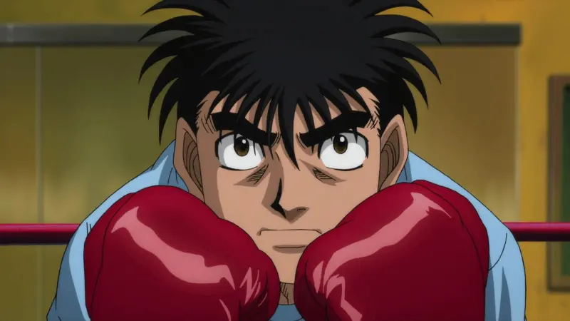 Ippo Makunouchi looking determined while holding up his red boxing gloves in the sports anime Hajime no Ippo.