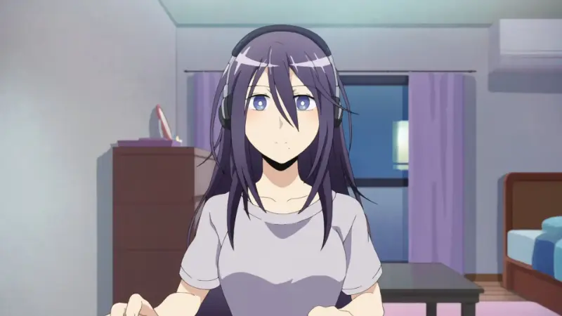 Moriko Morioka sits wide-eyed at her computer desk in a dark bedroom wearing a casual grey t-shirt and gaming headphones.